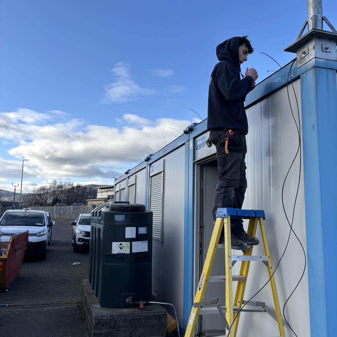 Man up ladder installing wires in Carrickfergus, County Antrim